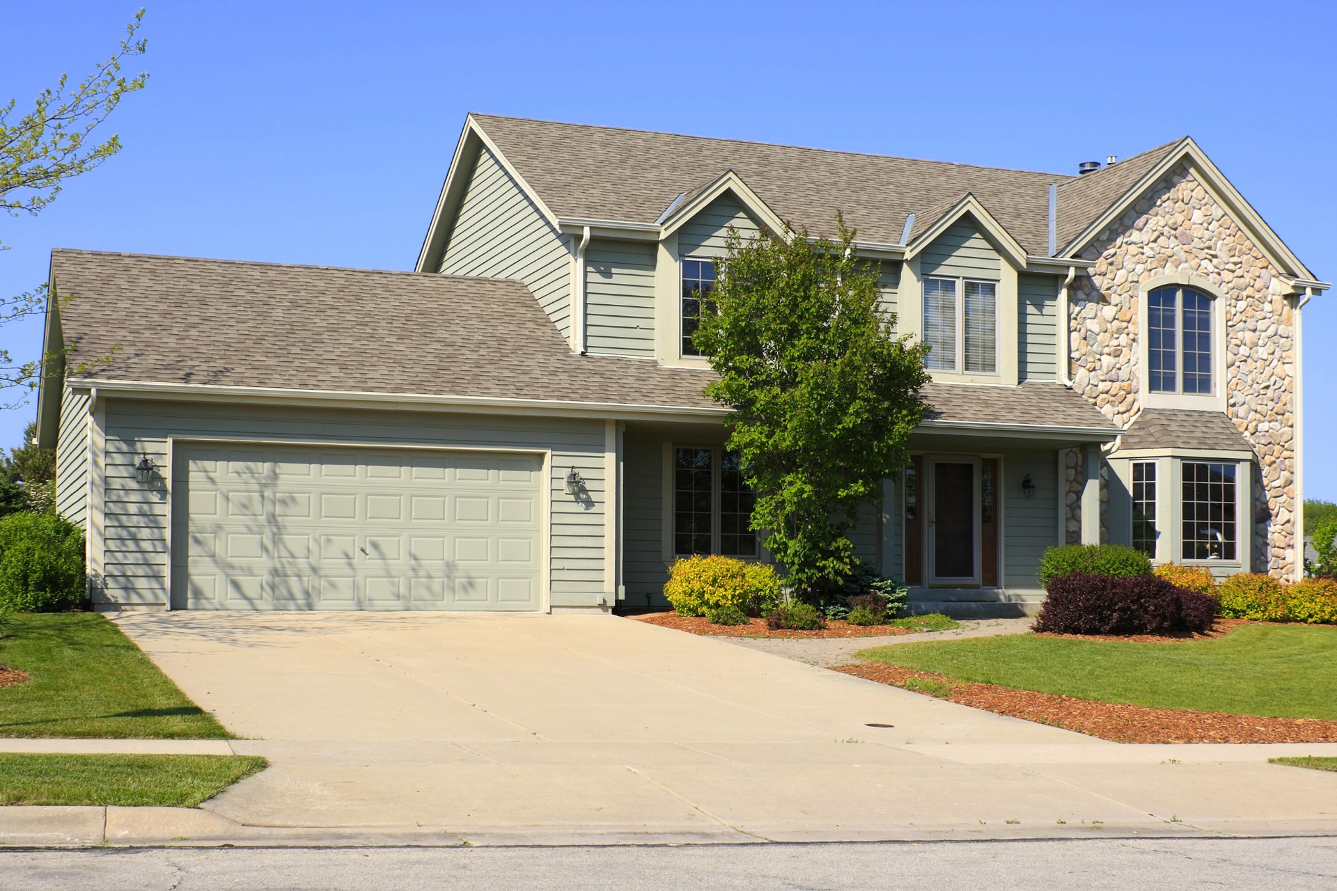 A white concrete driveway leading to a modern home in Joliet, IL.