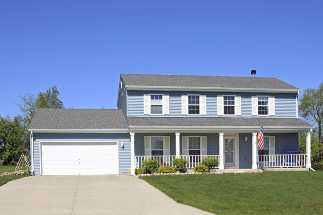 A white concrete driveway in front of a sky-blue home in Joliet, IL.