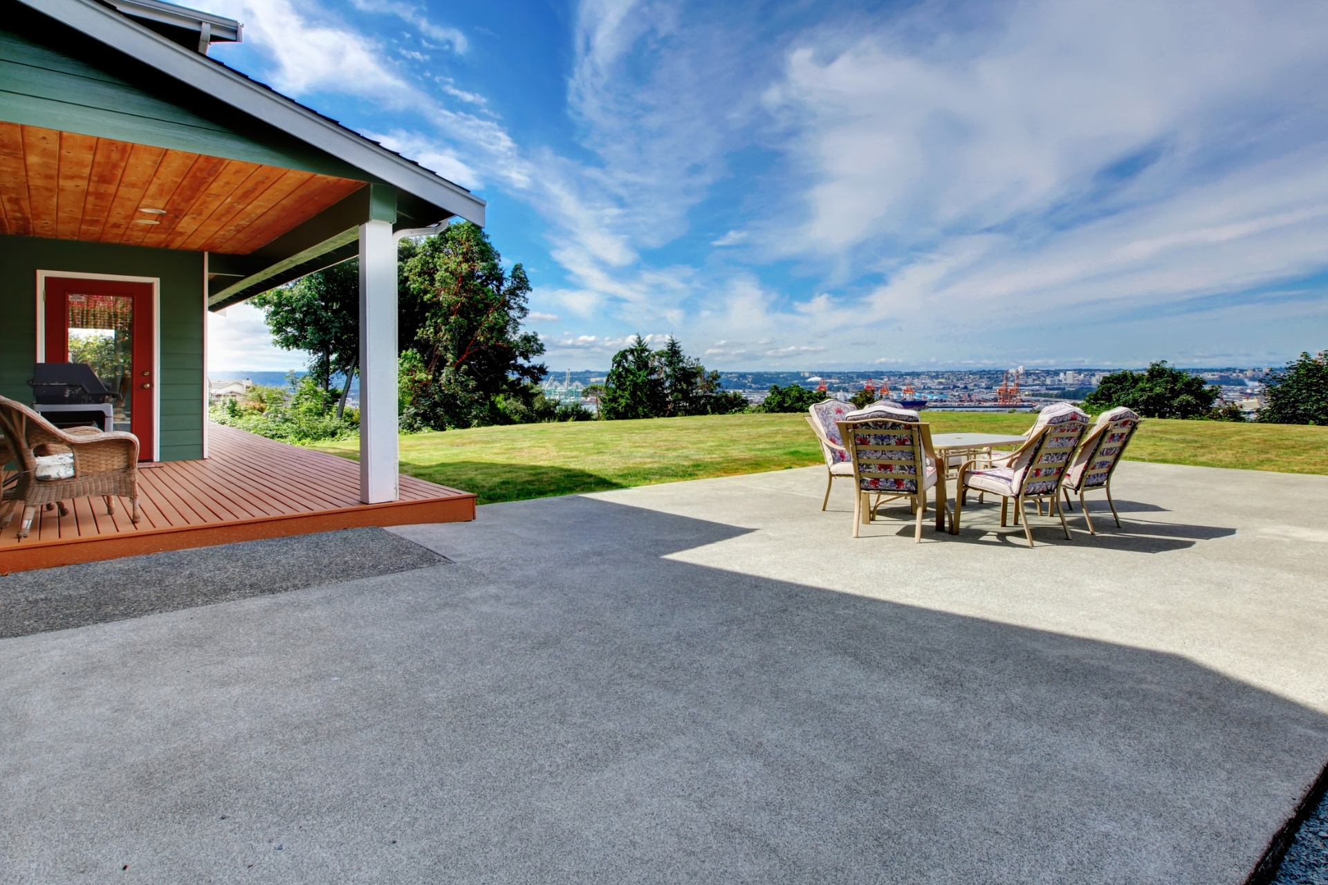 A large concrete patio with a furniture set under a blue sky.