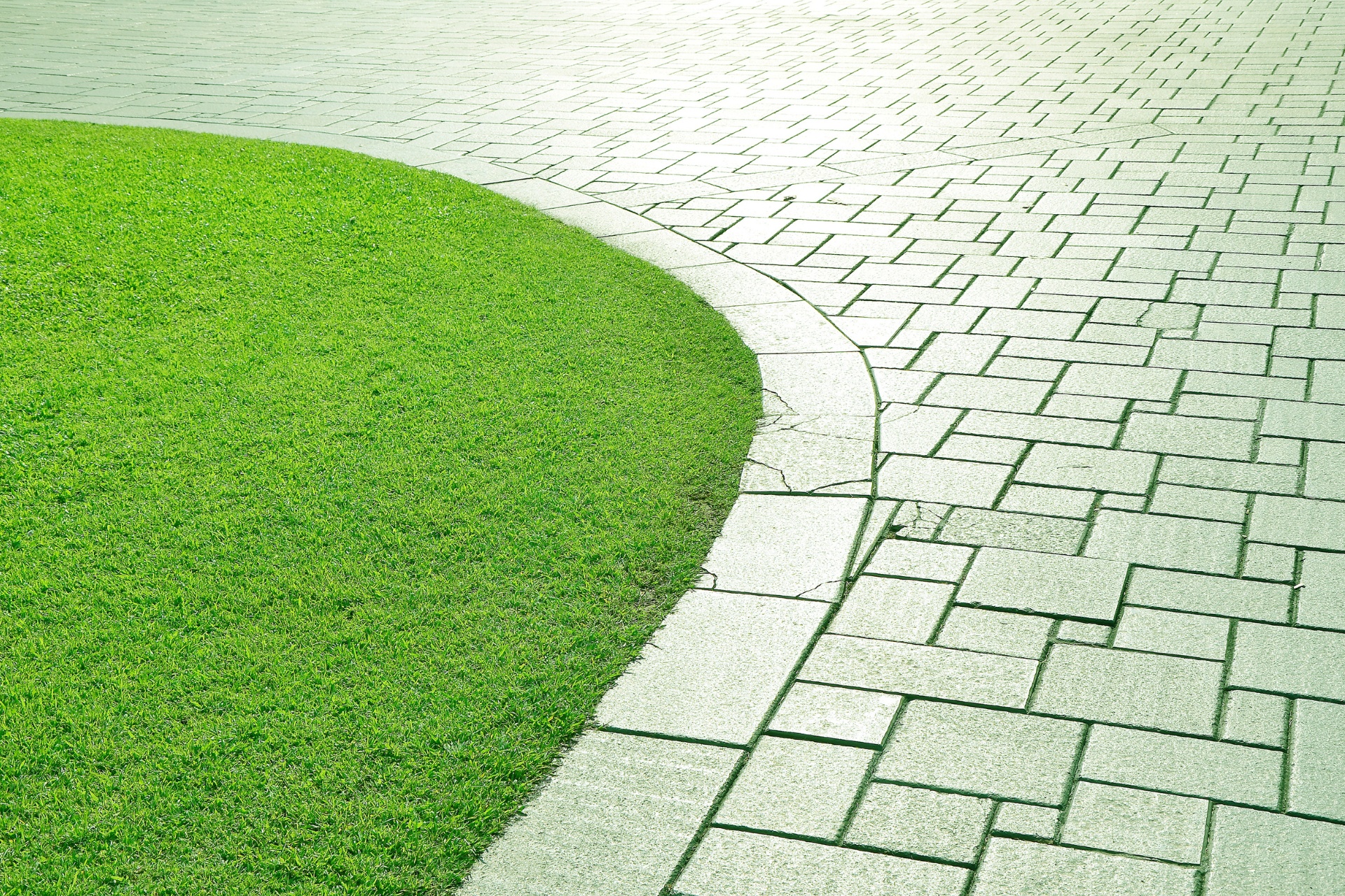 A custom, sealed concrete walkway bordered by green grass.